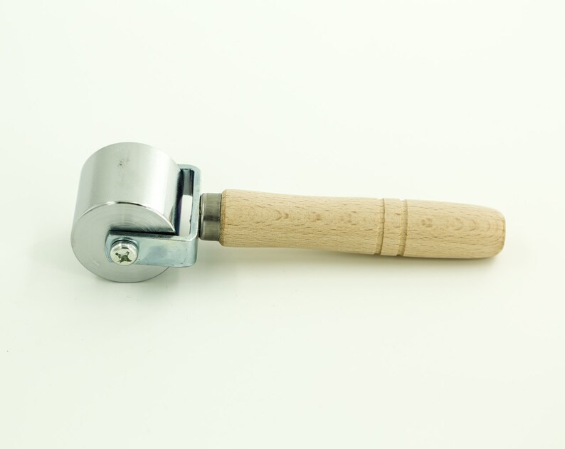 May include: A silver roller with a wooden handle. The roller is used for smoothing out surfaces.