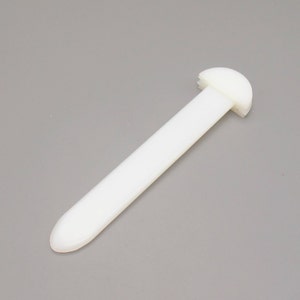 May include: White plastic tool with a rounded end and a flat, rectangular handle.