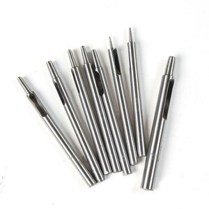 May include: A set of eight silver metal leather hole punches of varying sizes. The punches are arranged in a fan shape on a white background.