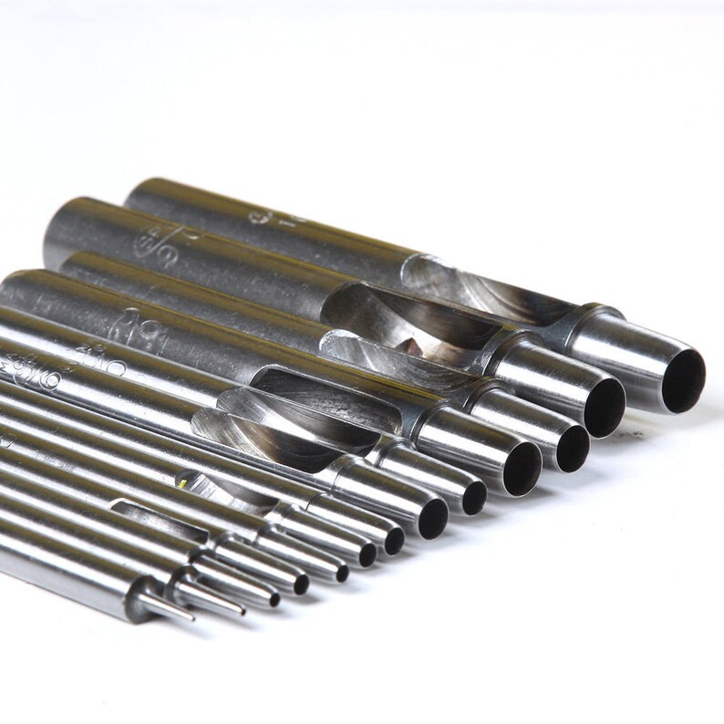 May include: A set of 9 silver metal hole punch tools with different sized holes. The tools are arranged in order of size, with the largest hole at the top and the smallest hole at the bottom.
