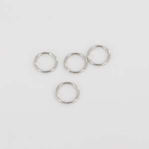 Puede incluir: Cuatro anillos de salto plateados, cada uno con una forma circular y un acabado liso y pulido.
