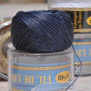 Può includere: Un'bobina di filo di lino blu scuro con il testo "FIL DE LIN n°40" e "Fabriqué en France" sull'etichetta.