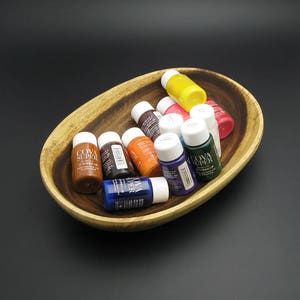Könnte beinhalten: Eine Holzschale gefüllt mit kleinen Flaschen Farbe in verschiedenen Farben, darunter Braun, Orange, Blau, Grün, Rot und Gelb. Die Flaschen sind mit "COVA SUPER" beschriftet.