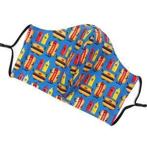 May include: A blue face mask with a repeating pattern of cartoon hot dogs, hamburgers, and mustard bottles. The hot dogs and hamburgers have smiling faces.