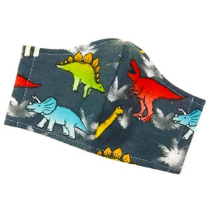 May include: A gray fabric face mask with a dinosaur print. The dinosaurs are red, green, blue, and yellow.
