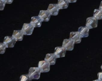May include: A strand of clear crystal beads with a faceted, pointed shape. The beads are strung on a clear thread and are arranged in a straight line.