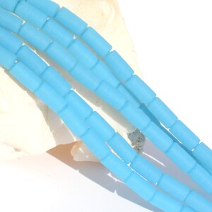 May include: A strand of light blue glass beads, each bead is a cylinder shape with rounded edges.