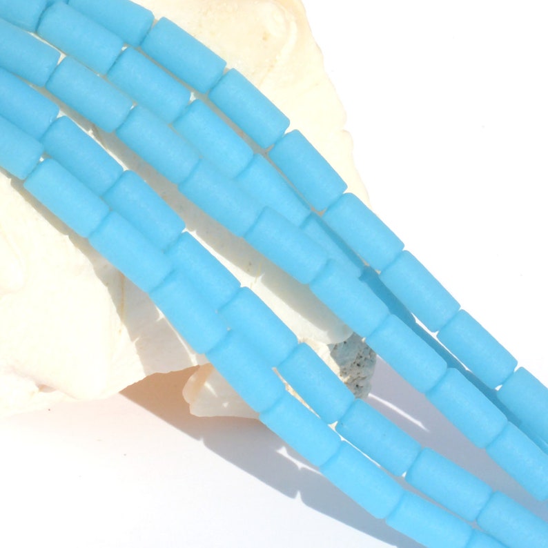 May include: A strand of light blue glass beads, each bead is a cylinder shape with rounded edges.