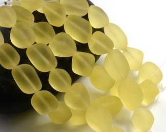 Può includere: Una collana di perline di vetro giallo pallido, ogni perla ha una forma ovale liscia e arrotondata. Le perline sono infilate su un filo trasparente e sono disposte a cascata.