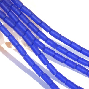 May include: A strand of blue glass beads, each bead is a cylinder shape with a frosted finish.