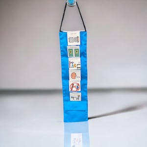 May include: A blue visual support tool with velcro tabs and various picture cards. The cards include images of a seat belt, restroom, physical therapy, using words, no bad behavior, and break time.