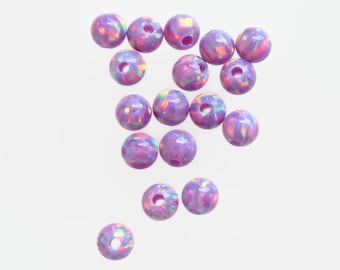 Könnte beinhalten: Eine Gruppe von 18 regenbogenfarbenen lila Perlen mit einem Loch in der Mitte. Die Perlen haben einen leicht rosa und blauen, schillernden Glanz.