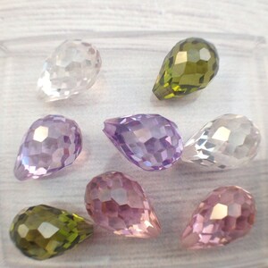 May include: Assortment of eight faceted teardrop-shaped glass beads in various colors, including clear, purple, pink, and green.