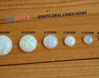 May include: Six white opal cabochons of varying sizes, from 4.00 mm to 12.00 mm, arranged in a row on a wooden surface.  The text "WHITE OPAL CABOCHONS" is printed above the stones.