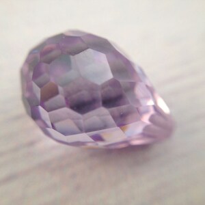 May include: A faceted, light purple crystal shaped like a teardrop.