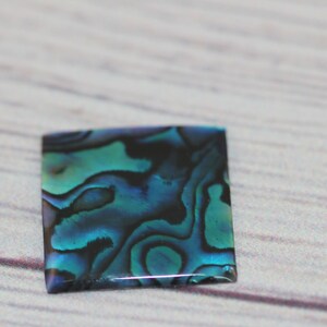 May include: A rectangular piece of iridescent abalone shell with blue, green, and black swirls.