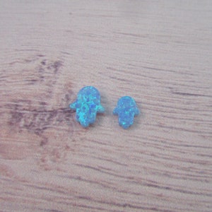 May include: Two small blue opal hamsa hand charms. The hamsa hand is a symbol of protection and good luck.