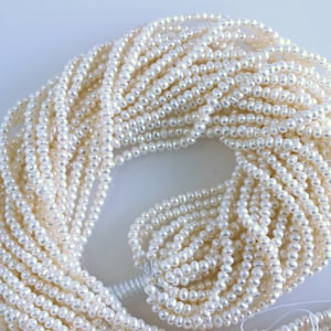 May include: A strand of white freshwater pearls, ideal for jewellery making. The pearls are small and consistent in size, with a smooth, lustrous finish.