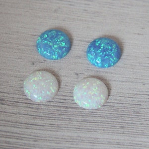 May include: Four round opal cabochons, two are white and two are blue. The opals have a sparkly, iridescent finish.