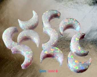 May include: A collection of ten iridescent white opal crescent moon shaped cabochons. The cabochons are approximately 1 inch in length and have a variety of rainbow colors.