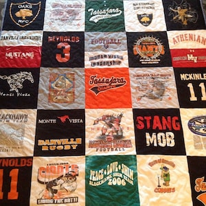 May include: A patchwork quilt made from t-shirts with various sports team logos and names, including "Tassajara Giants", "Monte Vista", "Danville Rugby", "Stang Mob", "McKinle 11", "Oaks RFC", "Blackhawk Swim Team", "Reynolds 3", "Athenian", and "Cobbies".