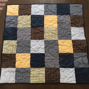 May include: A patchwork quilt with a variety of fabrics, including denim, plaid, and solid colors. The quilt is quilted with a swirling pattern.
