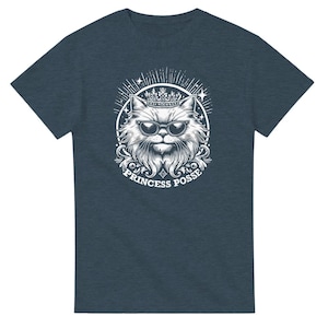Może przedstawiać: Koszulka w ciemnoniebieskim kolorze z białym nadrukiem przedstawiającym kota w okularach przeciwsłonecznych i koronie. Pod kotem widnieje napis "Princess Posse".