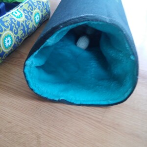 May include: A black and blue cat tunnel with a soft, blue, plush interior. A white ball is visible inside the tunnel.
