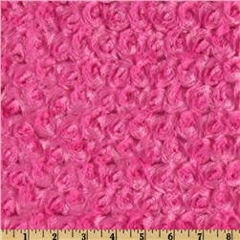 May include: Pink fluffy fabric with a rose pattern. The fabric is soft and plush, perfect for making blankets, pillows, or other crafts.