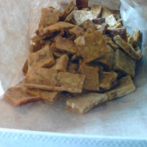 May include: A brown paper bag filled with crispy, golden brown crackers. The crackers are arranged in a pile and appear to be homemade.