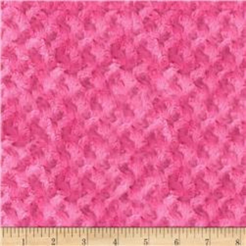 May include: Pink fuzzy fabric with a textured, swirling pattern. The fabric is soft and plush, perfect for crafting projects.