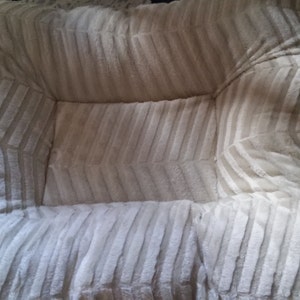 May include: A white and beige striped pet bed with a soft, plush texture.
