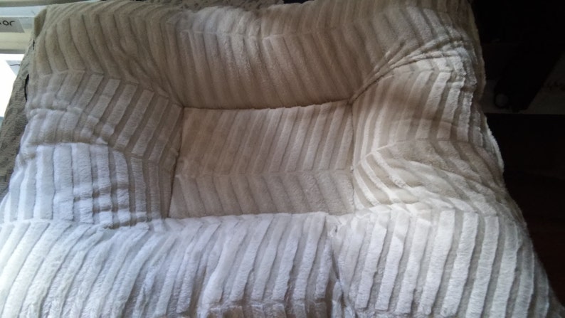 May include: A white and beige striped pet bed with a soft, plush texture.