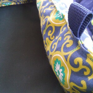 May include: A blue and yellow patterned fabric with a blue strap. The fabric has a floral design with white flowers.