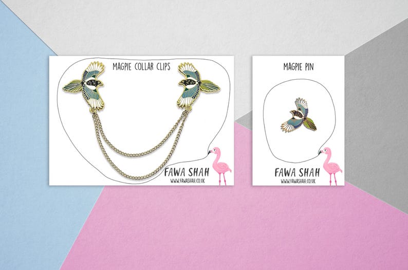 Puede incluir: Dos clips de collar de p&aacute;jaro urraca dorados con una cadena y un solo pin de p&aacute;jaro urraca. Los pines est&aacute;n en tarjetas blancas con flamencos rosas y el texto "Magpie Collar Clips" y "Magpie Pin". El texto "Fawa Shah" y una direcci&oacute;n de sitio web tambi&eacute;n est&aacute;n en las tarjetas.