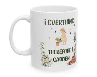 May include: A white ceramic mug featuring a green text graphic that reads "I OVERTHINK THEREFORE I GARDEN." The design includes a small illustration of a person watering a potted plant, surrounded by colorful floral and vegetable garden motifs.