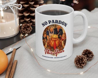 May include: A white ceramic mug featuring a graphic of a family at a dinner table with a roasted turkey wearing a red tie. The text reads NO PARDON This Year and THANKSGIVING 2026 - GRATEFUL SINCE NOV. 5. The mug has a standard handle and cylindrical body.