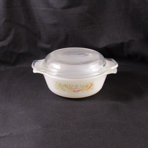 May include: White oval casserole dish with a glass lid. The dish has a floral design with green leaves, pink flowers, and yellow and red peppers.