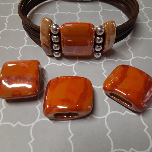 1 Large Peach Orange ceramic bead.  10mm flat slider, 2mm round leathers, 5mm flat leathers