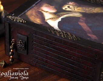 May include: A dark wooden box with a hinged lid, decorated with ornate metal accents and a painted image of a woman holding an owl. The box has a small metal charm attached to the side.