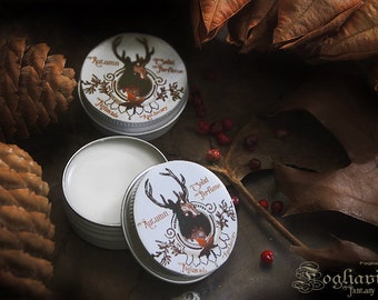 Peut inclure: Deux petits pots ouverts en métal argenté de parfum solide avec de la crème blanche à l'intérieur, à côté d'un pot fermé. Les couvercles présentent un motif de cerf avec les mots "Autumn Solid Perfume". L'arrière-plan comprend des feuilles d'automne et des pommes de pin.