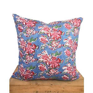 Peut inclure: Un coussin bleu avec un motif floral dans les tons de rose, rouge et vert. Le coussin est en coton et a une forme carr&eacute;e.