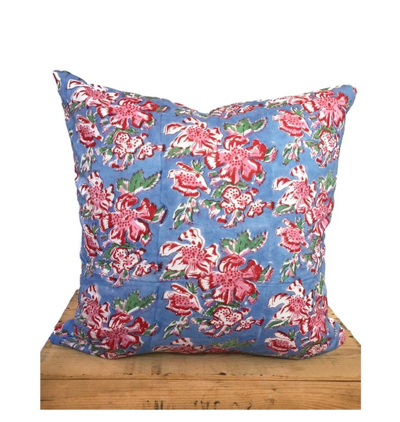 Peut inclure: Un coussin bleu avec un motif floral dans les tons de rose, rouge et vert. Le coussin est en coton et a une forme carr&eacute;e.