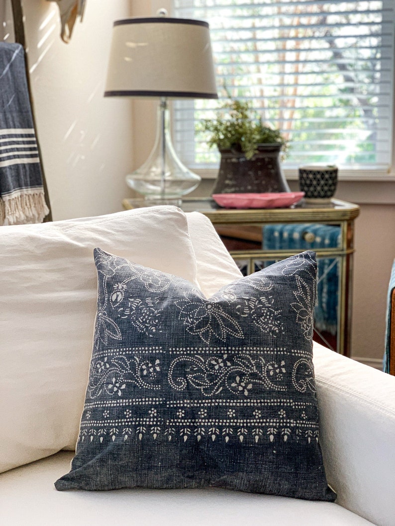 May include: A blue and white patterned throw pillow with a paisley design. The pillow is on a white couch with a white throw pillow behind it.