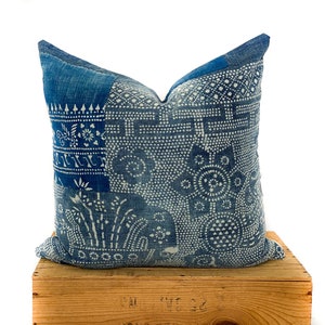 Peut inclure: Un oreiller bleu et blanc à motifs géométriques. L'oreiller est fait d'un tissu doux et texturé avec un léger brillant.