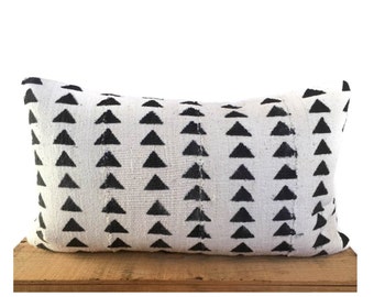 May include: A white and black patterned throw pillow with a geometric design of black triangles on a white background.