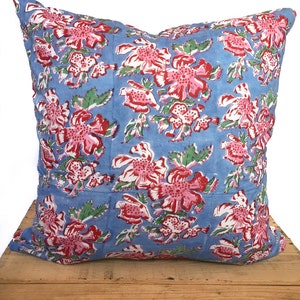 Peut inclure: Un oreiller bleu avec un motif floral dans les tons de rose, rouge et vert. L'oreiller est en coton et a une forme carr&eacute;e.