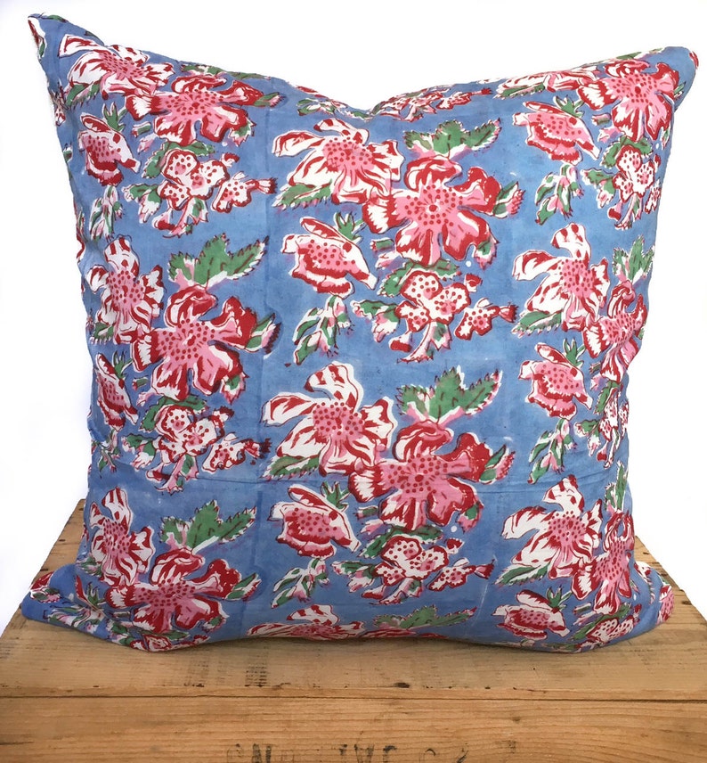 Peut inclure: Un oreiller bleu avec un motif floral dans les tons de rose, rouge et vert. L'oreiller est en coton et a une forme carr&eacute;e.
