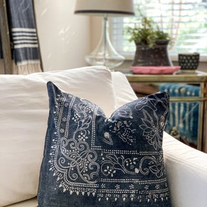 May include: A blue throw pillow with a white paisley pattern on a white couch.