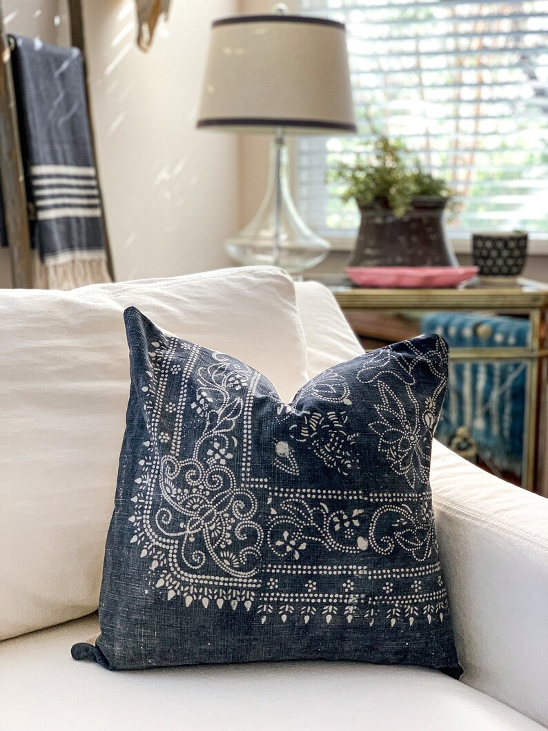 May include: A blue throw pillow with a white paisley pattern on a white couch.
